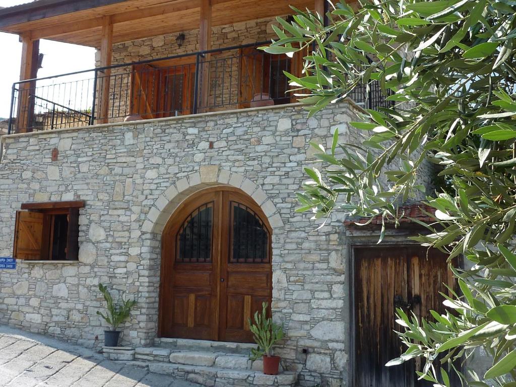 a stone house with a wooden door and a balcony at The House of Pericles in Silikou