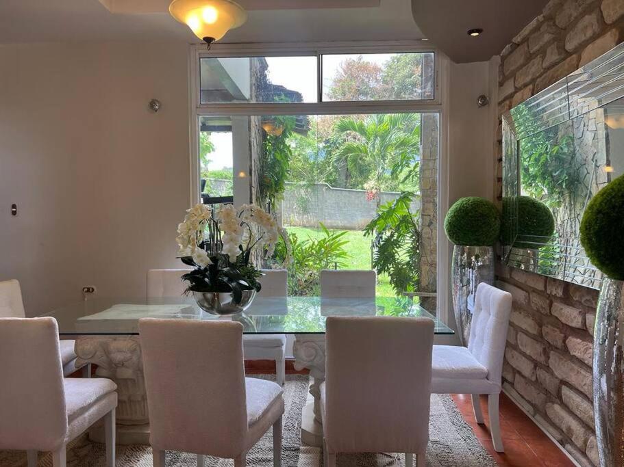 une salle à manger avec une table en verre et des chaises blanches dans l'établissement Casa dentro del Campo de Golf, à Comayagua