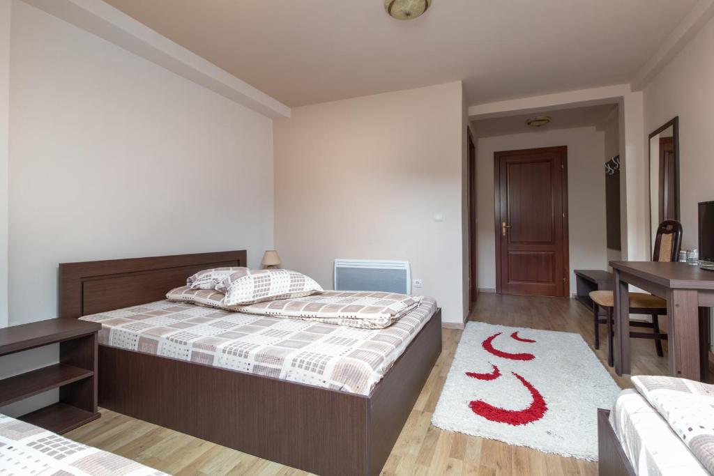 a bedroom with a bed and a red snake rug at Pensiunea Popasul Ursilor in Chişcău