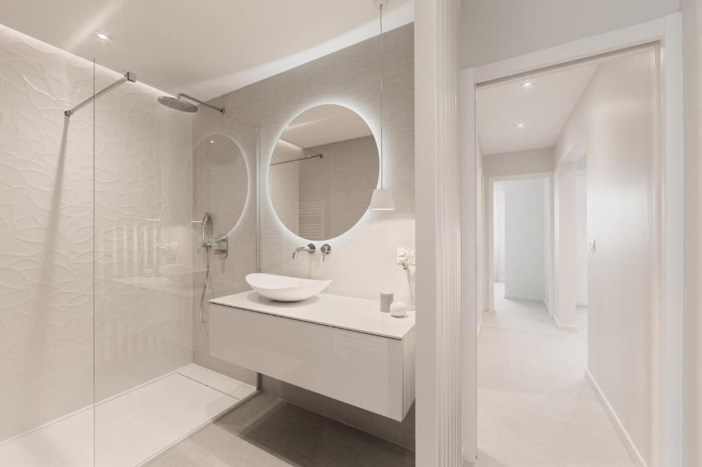 une salle de bain blanche avec un lavabo et un miroir dans l'établissement Luna mia 500 m du lac, à Annecy