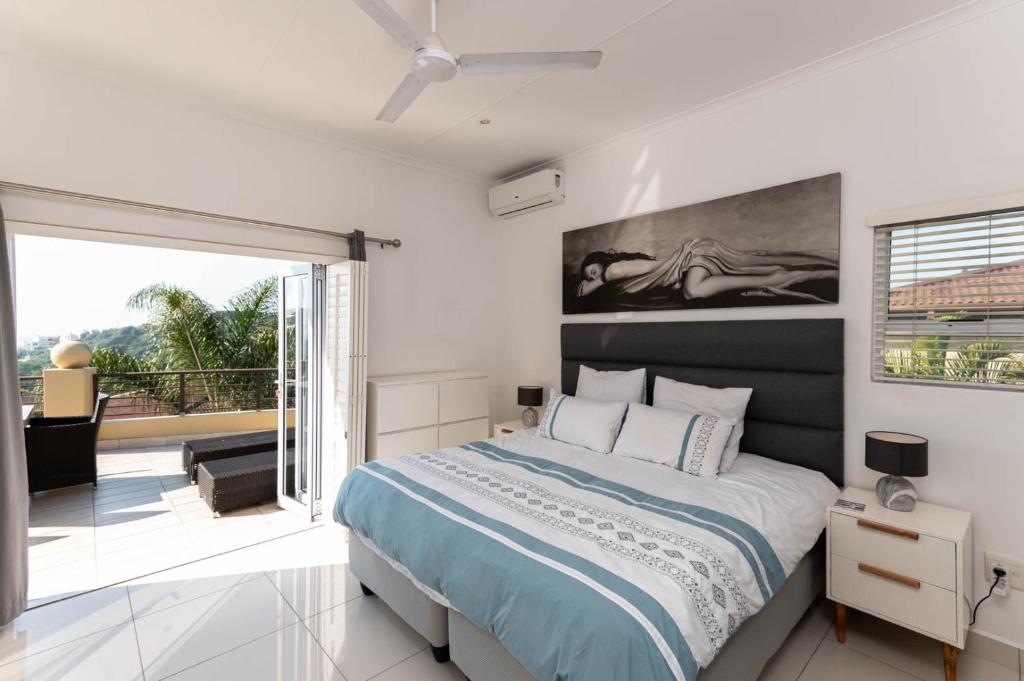 a bedroom with a large bed and a balcony at Bayridge 48 ~ Penthouse in Ballito
