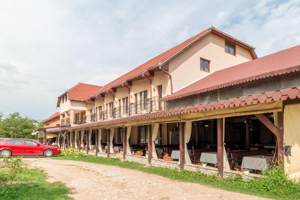 a building with a red car parked in front of it at Pensiunea Popasul Ursilor in Chişcău