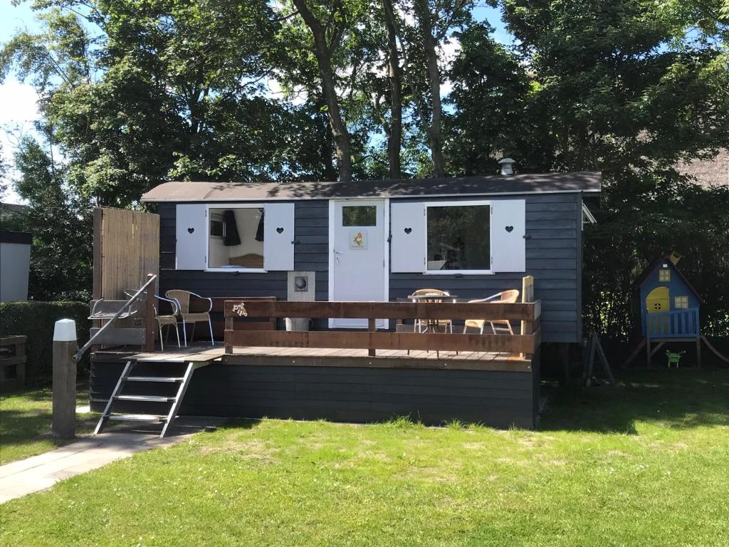 a tiny house with a porch and a bench at Tiny house Roodborstje in Oudesluis