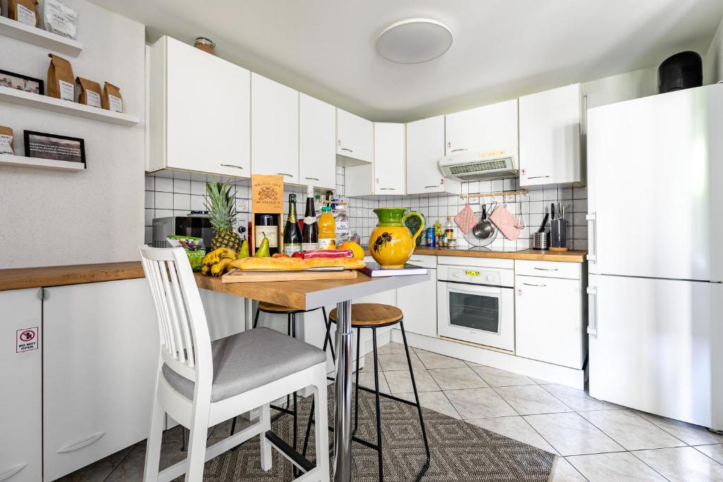 kuchnia z białymi szafkami, stołem i krzesłami w obiekcie * Loft 3 pièces/Calme, tout équipé @ Centre Ville w Strasburgu