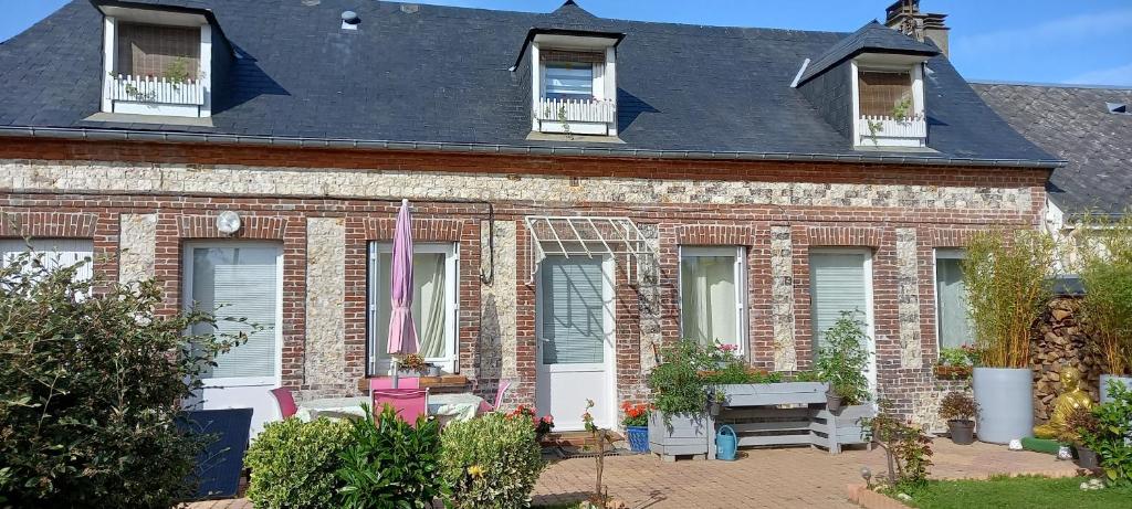 ein rotes Backsteinhaus mit Fenstern und einer Bank in der Unterkunft Le Jardin des Poules in Thiétreville