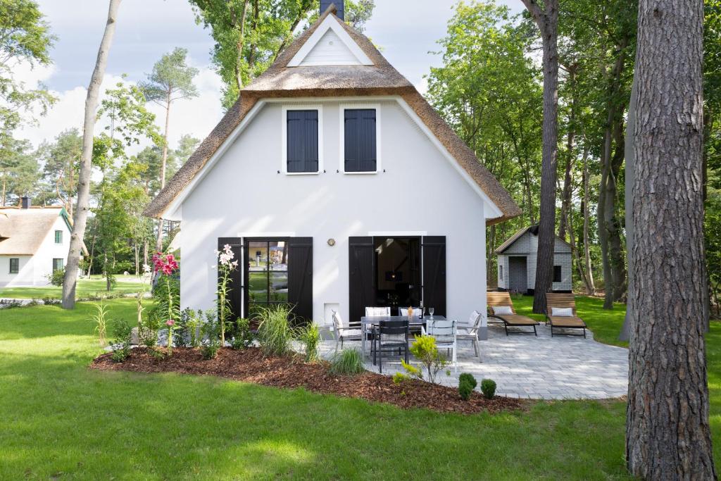 une maison blanche avec un toit de chaume dans l'établissement Neues Friesenhaus Oogenstern Ferienhaus Usedom -stufenlos im Erdgeschoß- ruhige Lage, à Zirchow