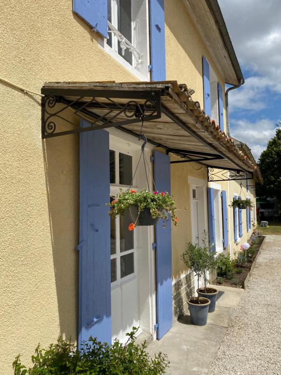 ein Gebäude mit blauen Türen und Topfpflanzen darauf in der Unterkunft L'ancien Cafe - Suites and Gites 
