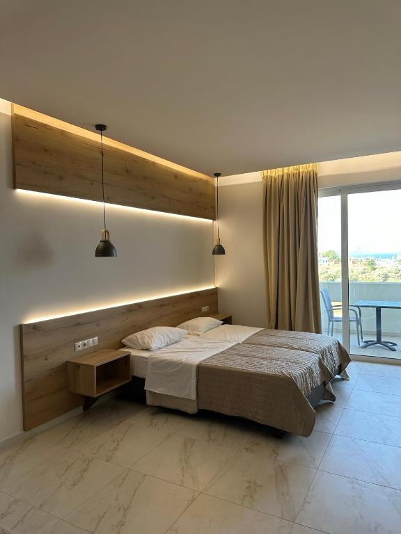 a bedroom with a large bed and a large window at Faliraki Star in Faliraki
