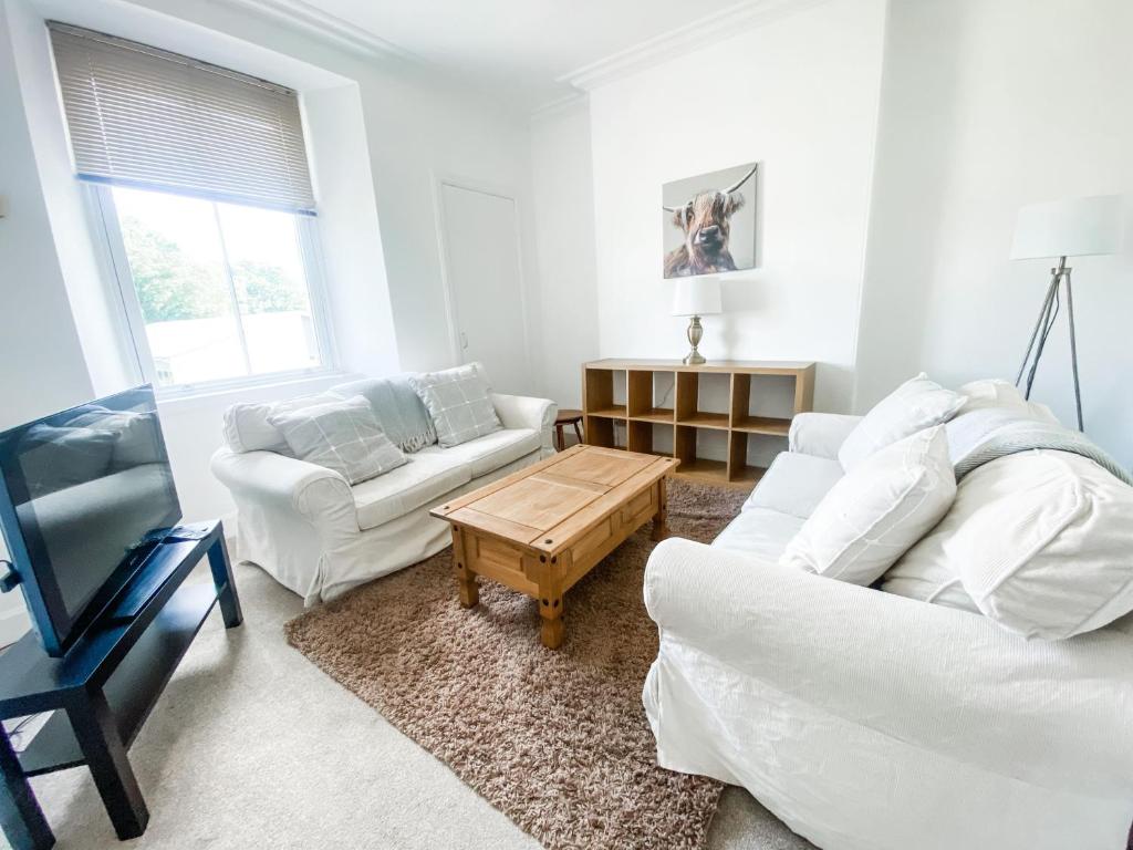 a living room with two white couches and a coffee table at Pipelands Road in St. Andrews