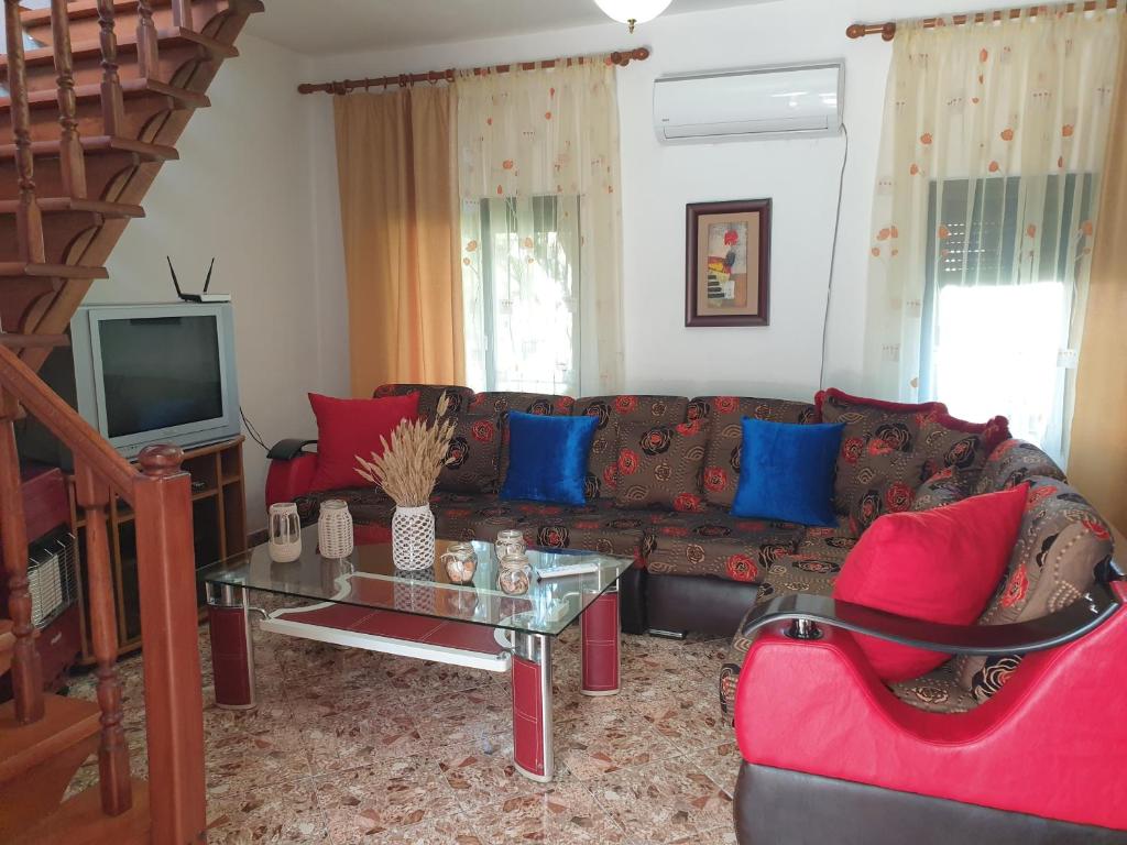 ein Wohnzimmer mit einem roten Sofa und blauen Kissen in der Unterkunft Eni's Villa, 5km From Shengjini Beach in Lezha