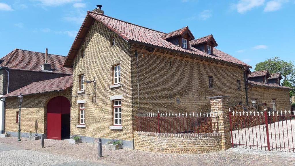 un grande edificio in mattoni con una recinzione di fronte ad esso di Boerderijwoning Elsloo a Elsloo