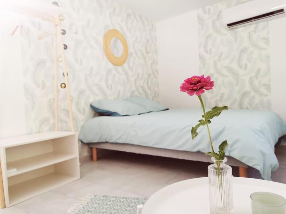 a room with a bed and a vase with a flower on a table at Belle dépendance de 30m2 avec terrasse et jardin in Villeneuve-lès-Avignon