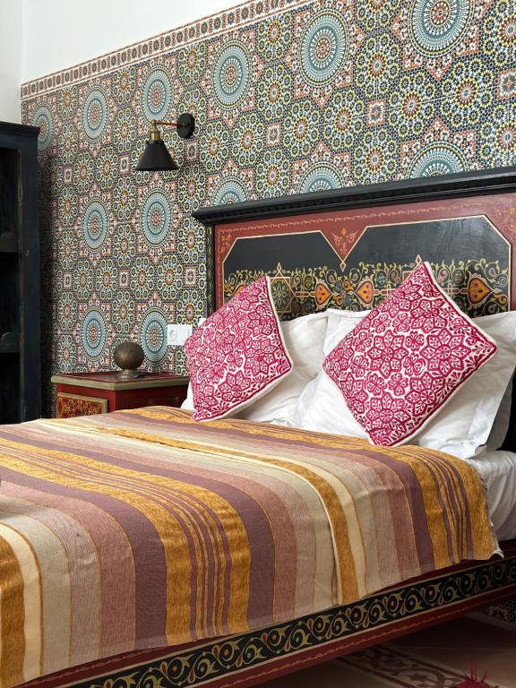 sypialnia z łóżkiem z różowymi poduszkami w obiekcie Riad Al Zahia w mieście As-Suwajra