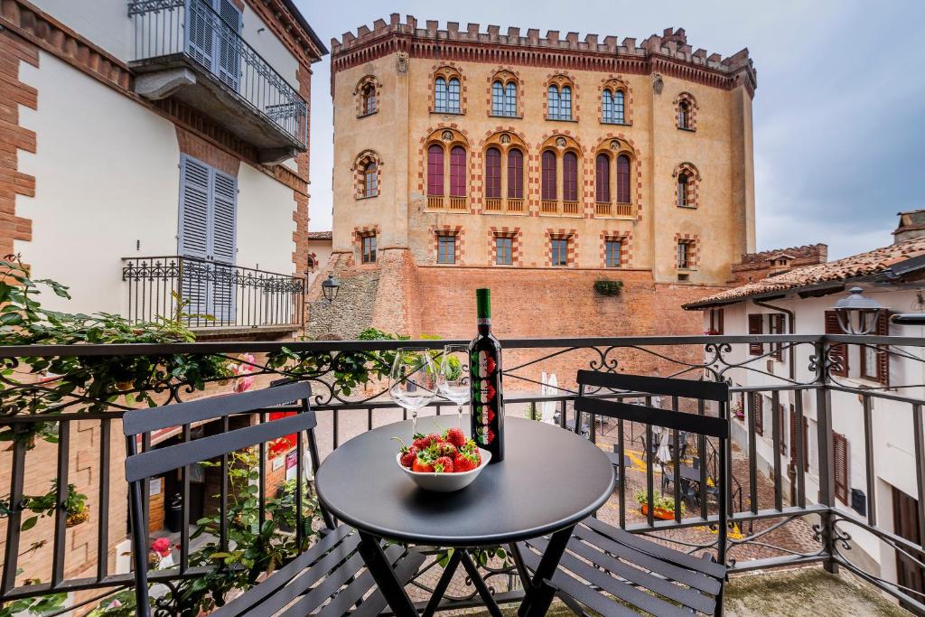 una mesa con un bol de fruta y una botella de vino en el balcón en CasaCastello Barolo, en Barolo