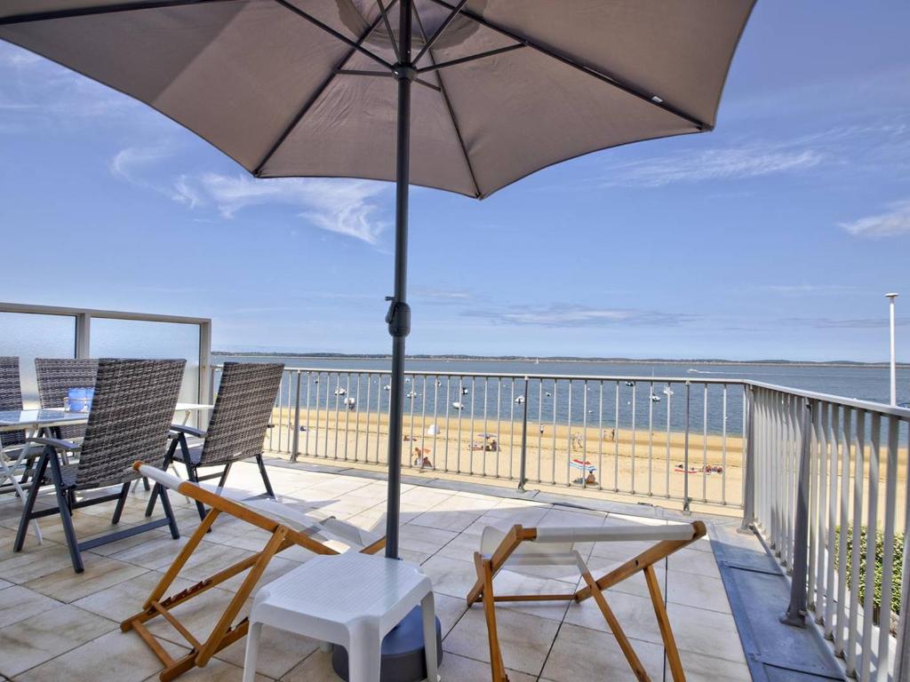 a patio with chairs and an umbrella and a table at Arcachon Pereire - T2 front de mer avec terrasse et parking, accès direct plage - FR-1-433-24 in Arcachon