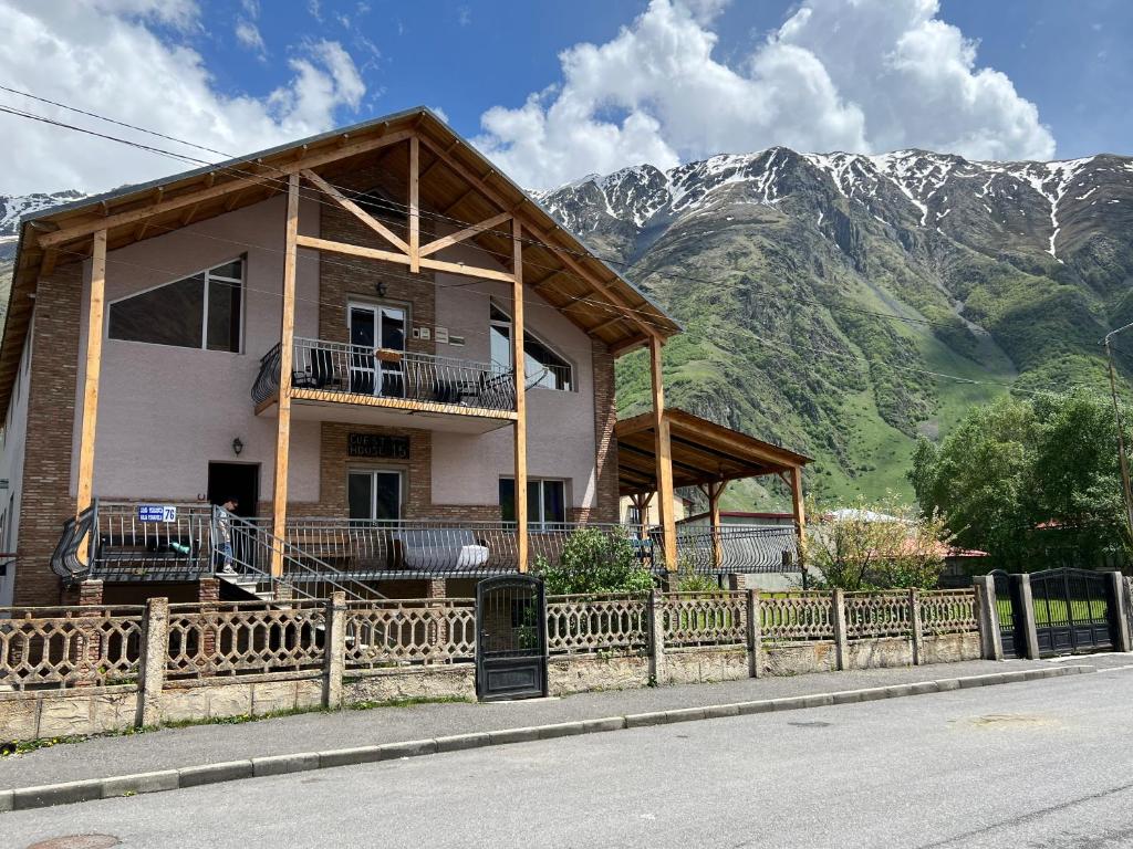 una casa con una valla delante de una montaña en Guest House 15, en Kazbegi