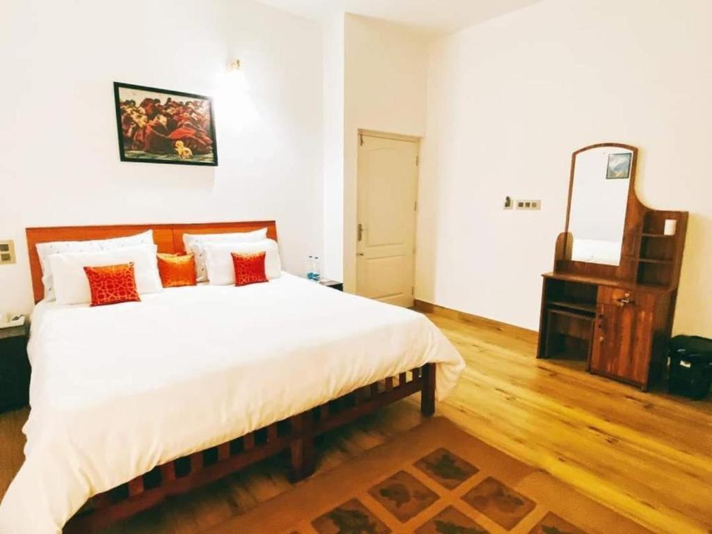 una camera con un grande letto e uno specchio di Tess Holistay Fort Kochi a Fort Kochi