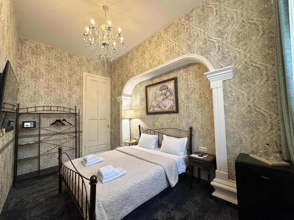 sypialnia z łóżkiem i żyrandolem w obiekcie Boutique Hotel Alegria w mieście Tbilisi City