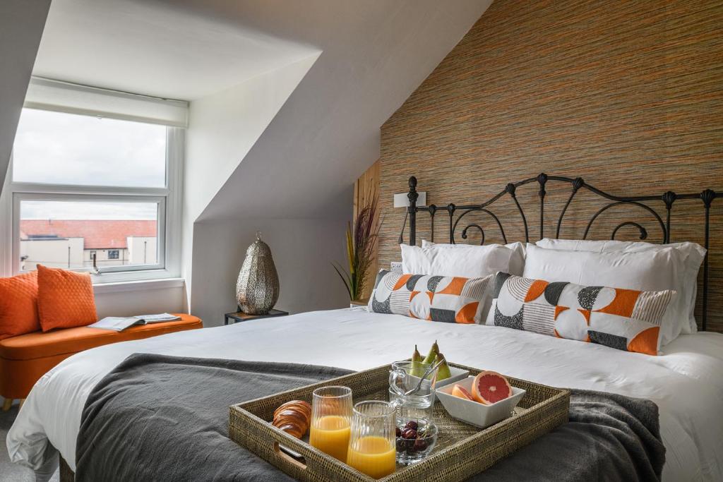een bed met een dienblad met fruit en drankjes erop bij Cludfan (Cosy Place) - in the heart of Llandudno in Llandudno