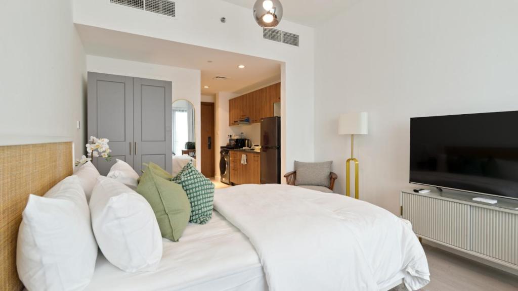 a white bedroom with a large white bed with pillows at Delightful Staycation in Masdar in Al Qurayyah