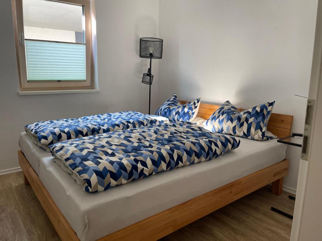a bed with blue and white sheets and a window at Ferienwohnung im wunderschönen Altmühltal in Wellheim