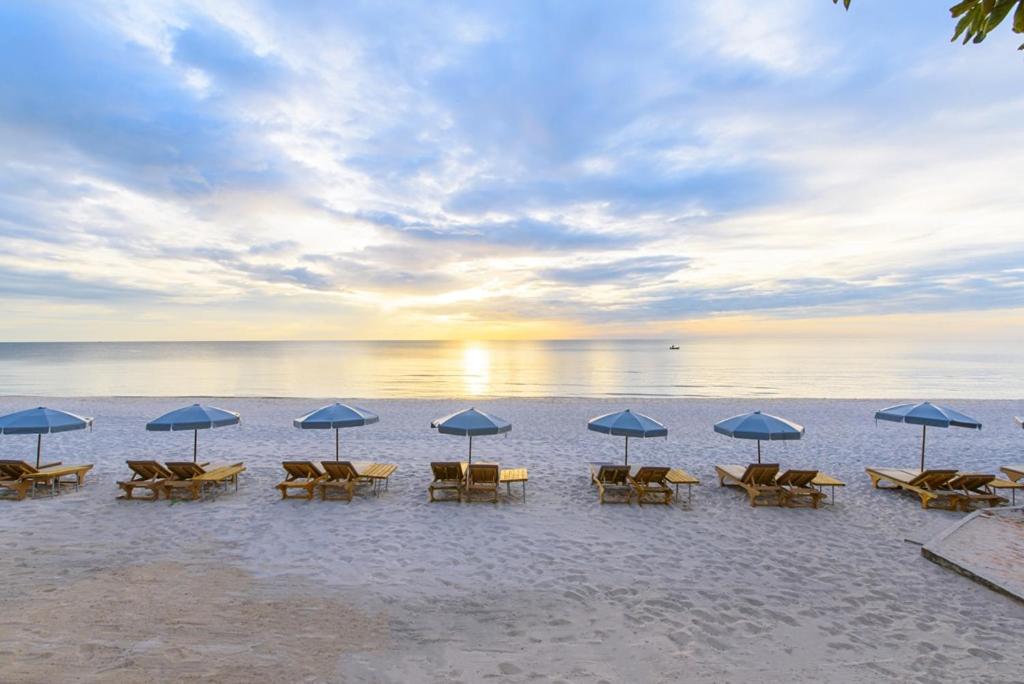 eine Gruppe von Stühlen und Sonnenschirmen am Strand in der Unterkunft Veranda Lodge in Hua Hin