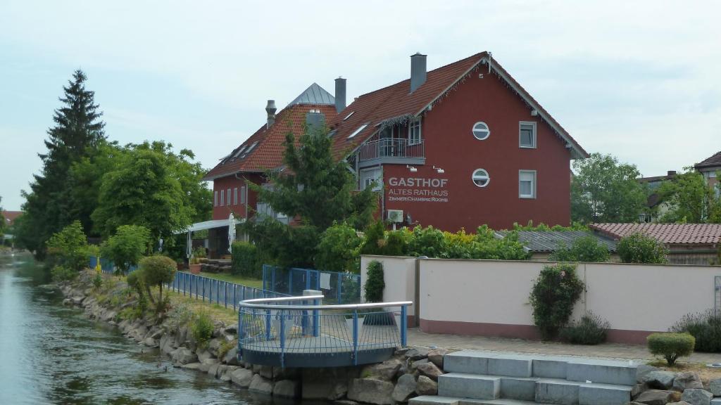 Gasthof Altes Rathaus garni في روست: مبنى احمر بجانب نهر به منزل