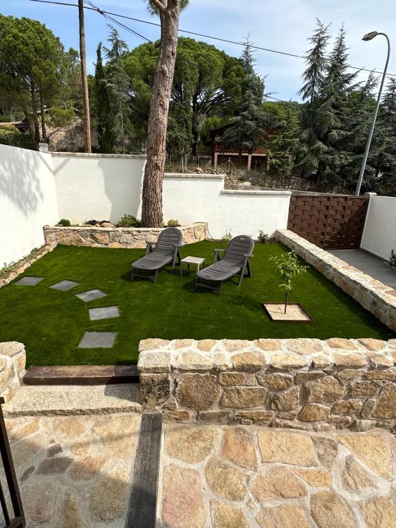 a yard with two chairs and a tree and grass at El secreto del pinar in Hoyo de Pinares