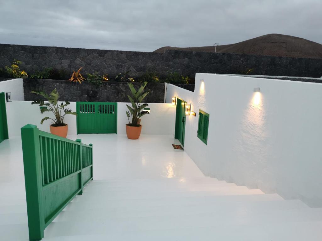 a white building with green doors and potted plants at Villa Tagoror in Tiagua