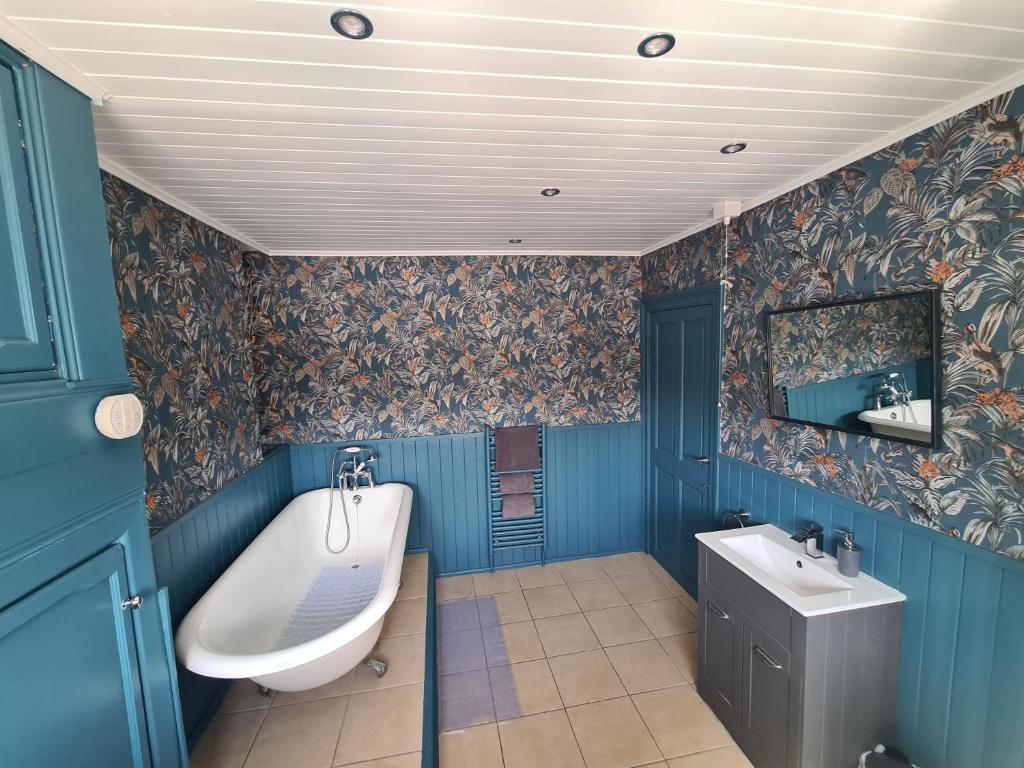 baño con paredes azules, bañera y lavamanos en Brownlow Townhouse 3 bedroom ideal for contractors and visitors, en Lurgan