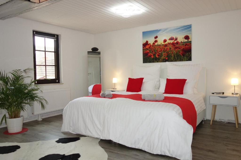 a white bedroom with a large bed with red pillows at HAPPY-HOMES - Up to 5 - Küche - W-LAN - Netflix - Honig - Terrasse in Altenstadt