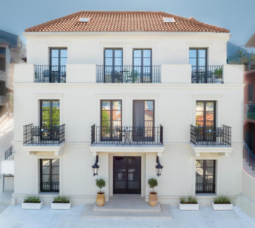een wit huis met zwarte ramen en balkons bij Argostoli Essence Suites in Argostoli