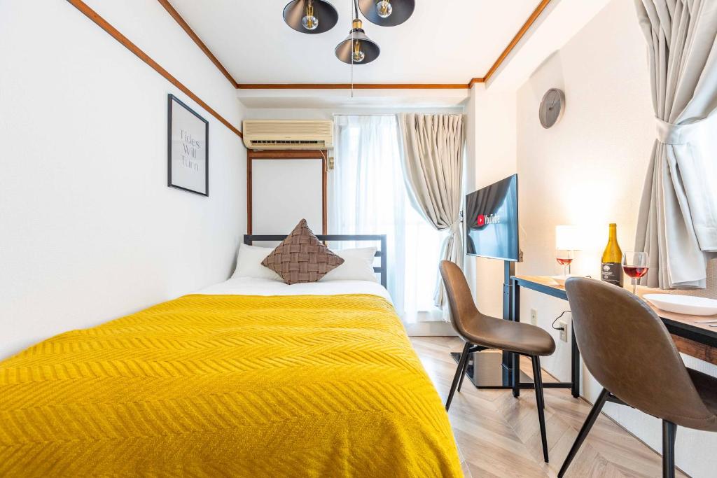 1 dormitorio con cama amarilla y escritorio en エステラス大阪ウエスト101 en Osaka