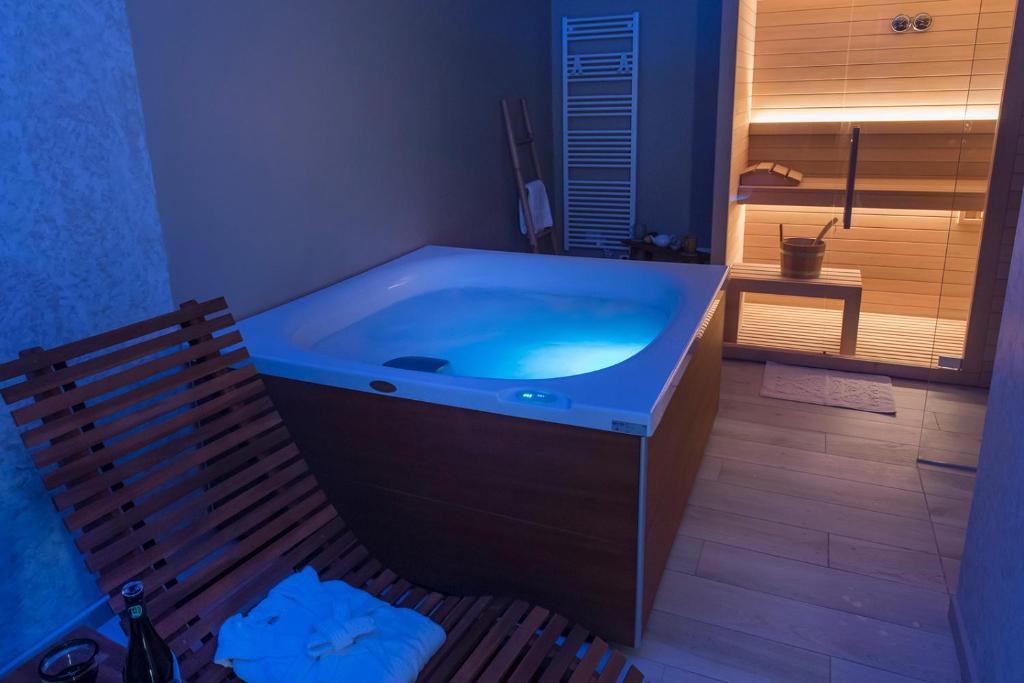 uma grande banheira azul numa casa de banho com um banco em Accanto Alle Mura Rooms & Relax Spa em Sirolo