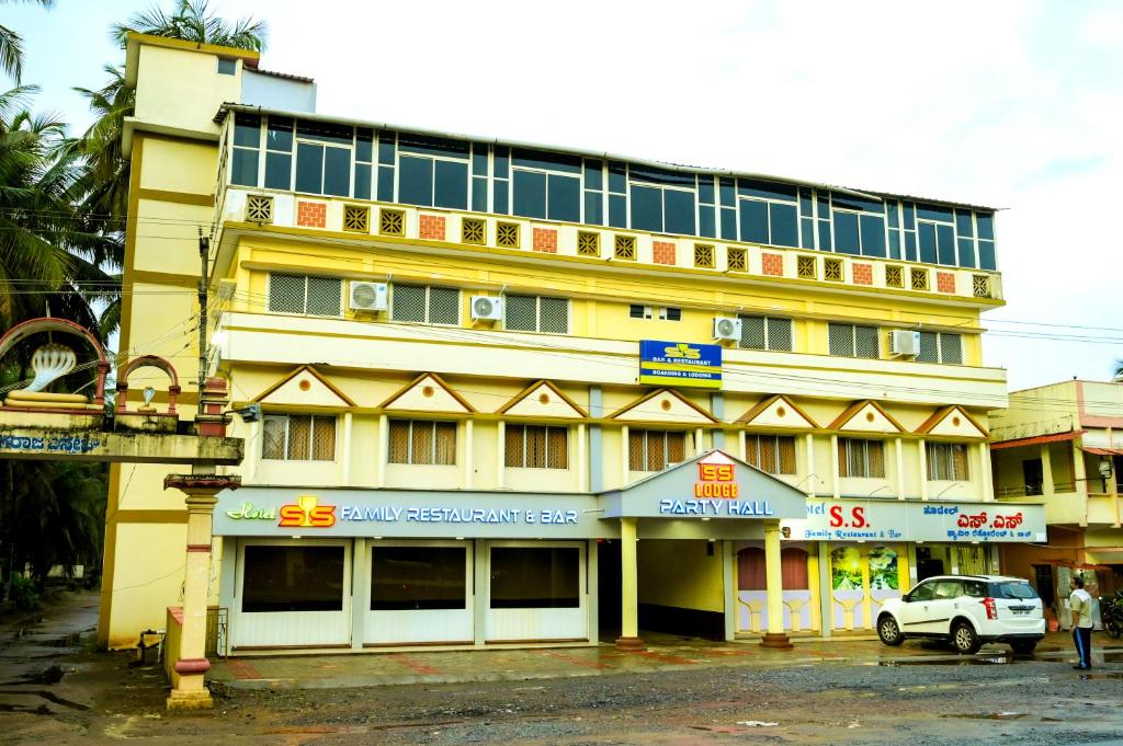 żółty budynek z samochodem zaparkowanym przed nim w obiekcie S S RESIDENCY w mieście Padubidri