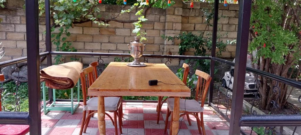 a wooden table and chairs on a balcony at Qonaq evi in Sheki