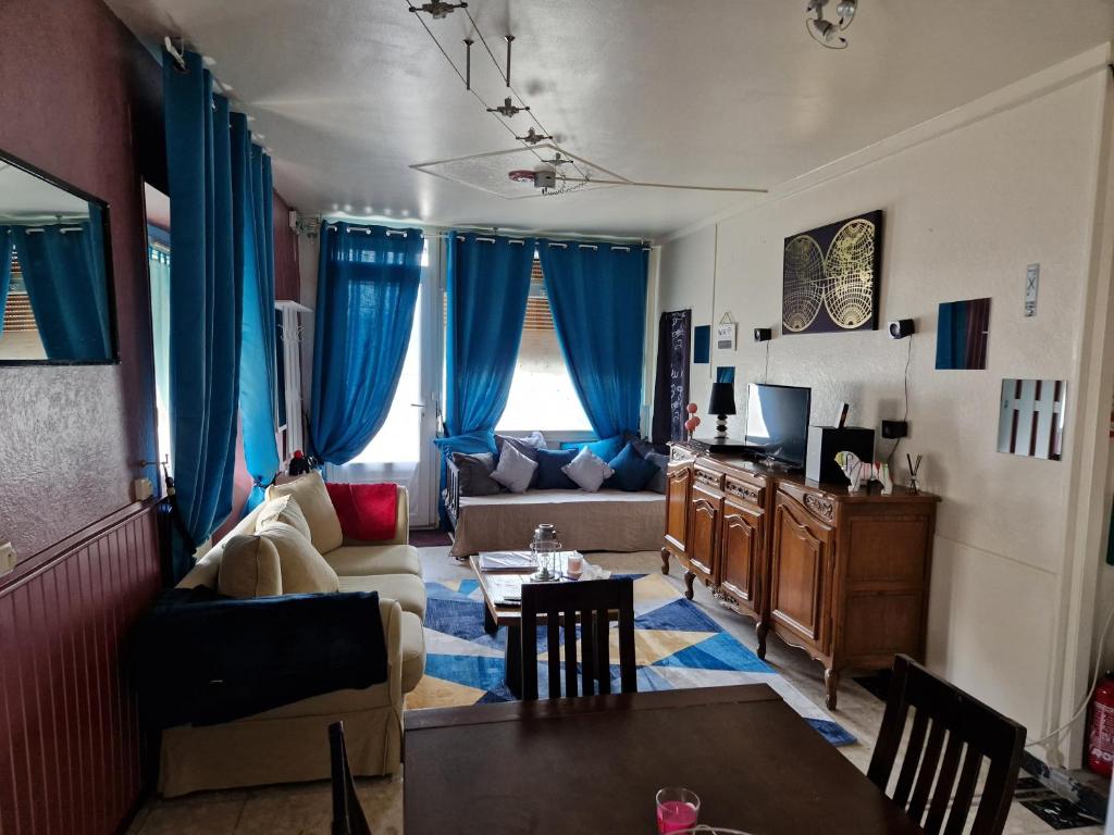 a living room with blue curtains and a couch at Appartement Le Dauphin 