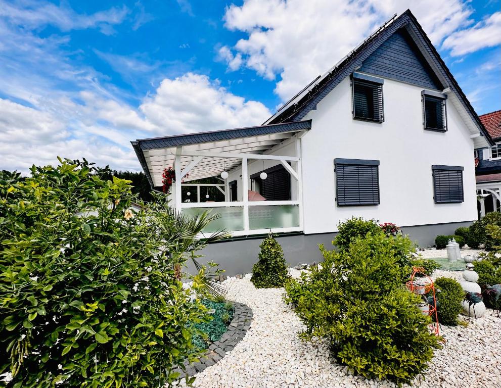 a white house with black windows and bushes at Ferienhaus zur Waldauer Höhe mit 3 SZ, 120qm & 40qm Balkon in Schleusingen