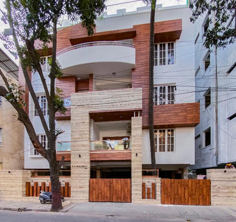 un edificio con un árbol delante de él en SS Mystic Apartotel, en Bangalore
