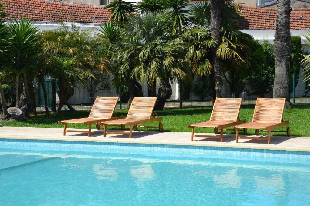 um grupo de cadeiras sentadas ao lado de uma piscina em Porto Concept Home - University Residence & Guesthouse - Pólo II Areosa no Porto