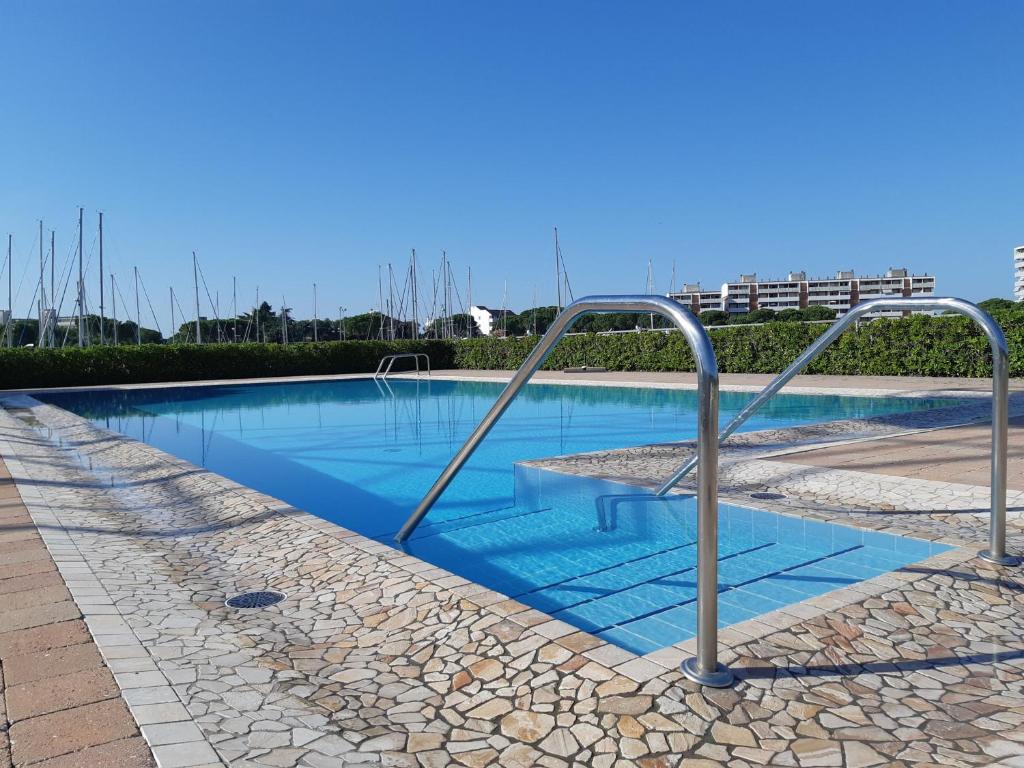 a swimming pool with blue water and metal rails at Villa a schiera con uso piscina in Aprilia Marittima