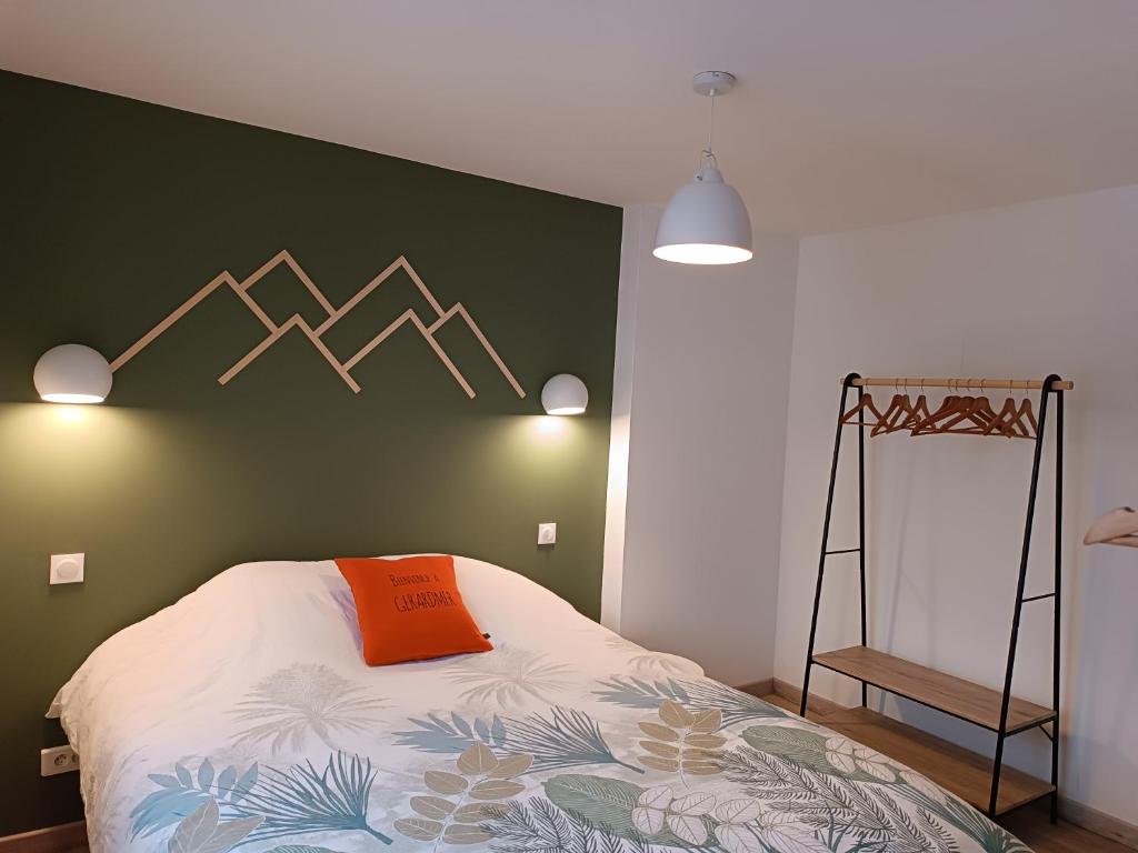 - un lit avec un oreiller orange sur un mur vert dans l'établissement Le Nesdel, à Gérardmer