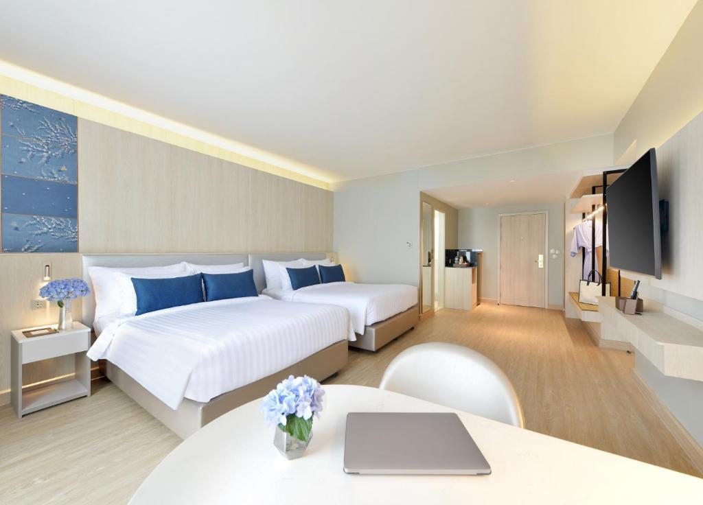 a hotel room with two beds and a tv at Centre Point Pratunam in Bangkok