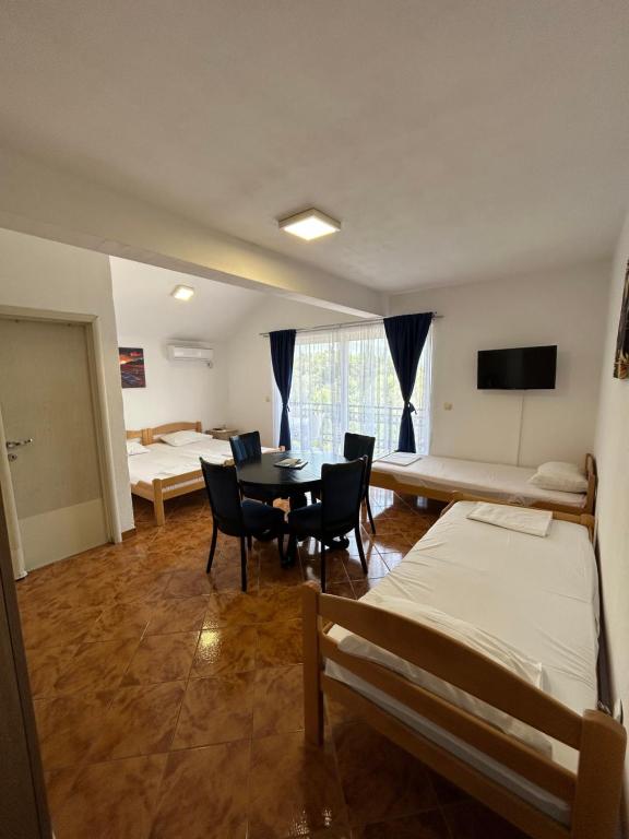 una habitación con dos camas y una mesa y sillas en Krašići apartmani Bozic, en Krasići