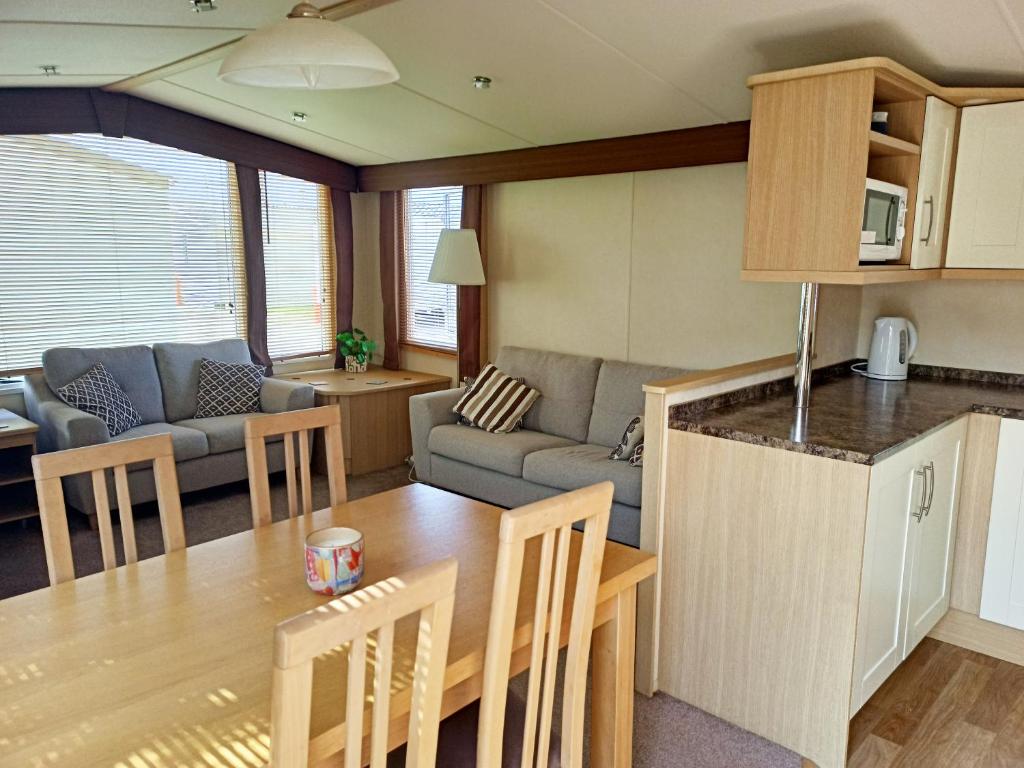 a kitchen and living room with a table and a couch at 2 Bedroom Static Caravan C3 on quiet park near Talacre and Prestatyn in Prestatyn
