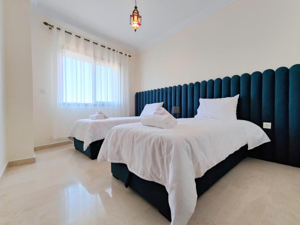 een slaapkamer met 2 bedden en witte lakens bij Appartment in Tanger City Center - 5min to The Beach - Free Parking in Tanger