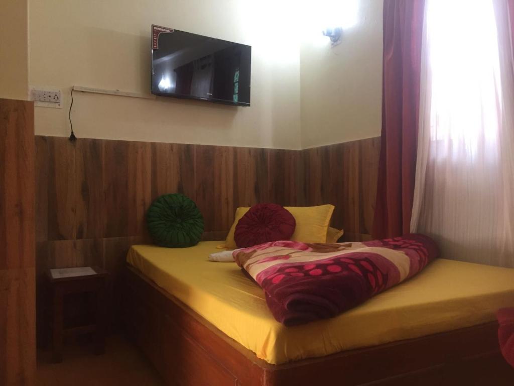een bed in een kamer met een televisie aan de muur bij International Youth Hostel and Homestay Kurseong Bazar in Kurseong