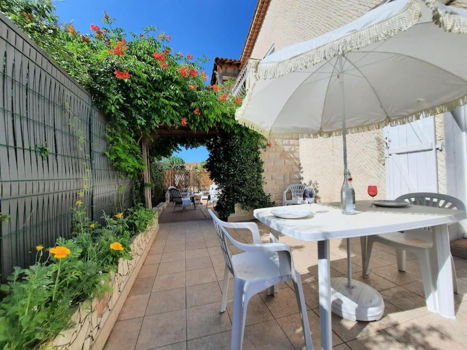 - une table et des chaises blanches avec un parasol sur la terrasse dans l'établissement LOCATION MAROTY, à Manosque