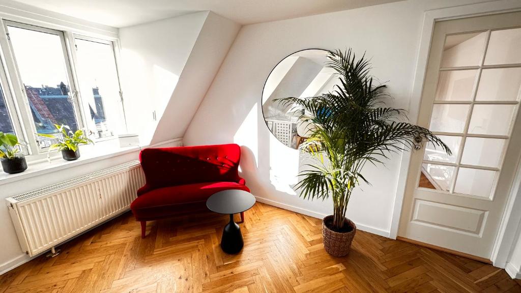 una sala de estar con una silla roja y una planta en Carolinas Apartment - Studie 4th floor, en Copenhague