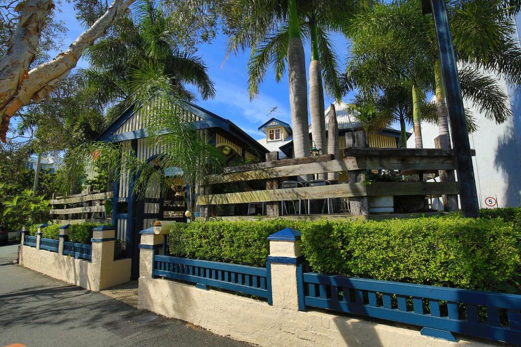 a blue fence in front of a building with palm trees at Brisbane Manor in Brisbane